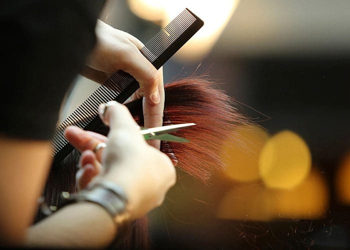 A person is cutting their hair with scissors.