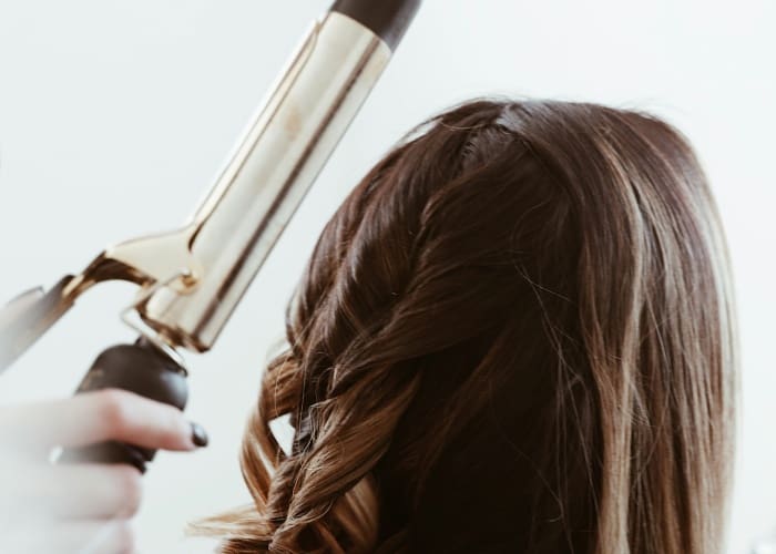 A woman blow drying her hair with a blow dryer.